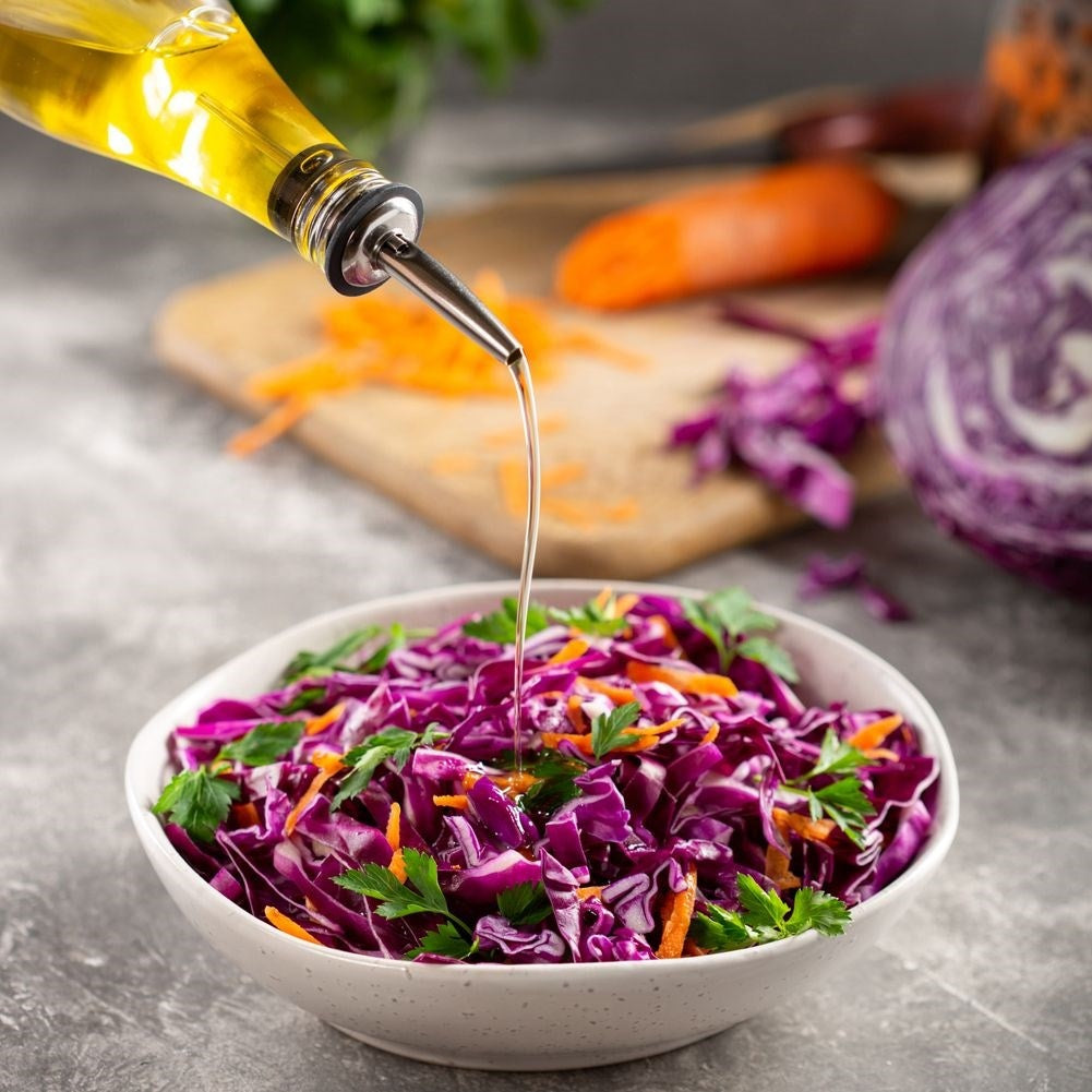 Se vierte aceite sobre una ensalada de col lombarda y zanahorias.