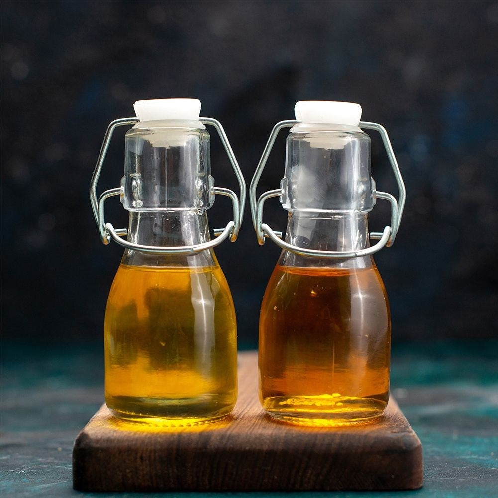 Dos botellas pequeñas de vidrio con cierre abatible, llenas de líquido amarillo y marrón.