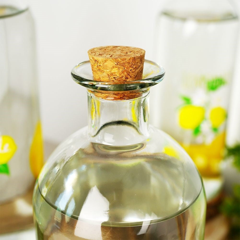 Primer plano de una botella de vidrio con corcho, llena de líquido transparente.