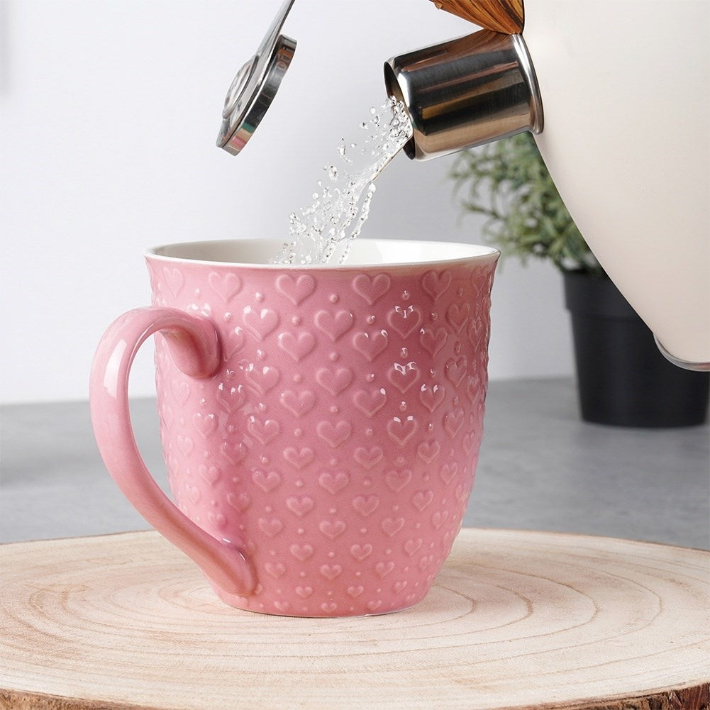 Se vierte agua en una taza rosa con corazones.