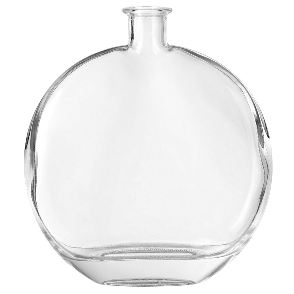 Un frasco redondo, transparente y vacío con cuello estrecho.