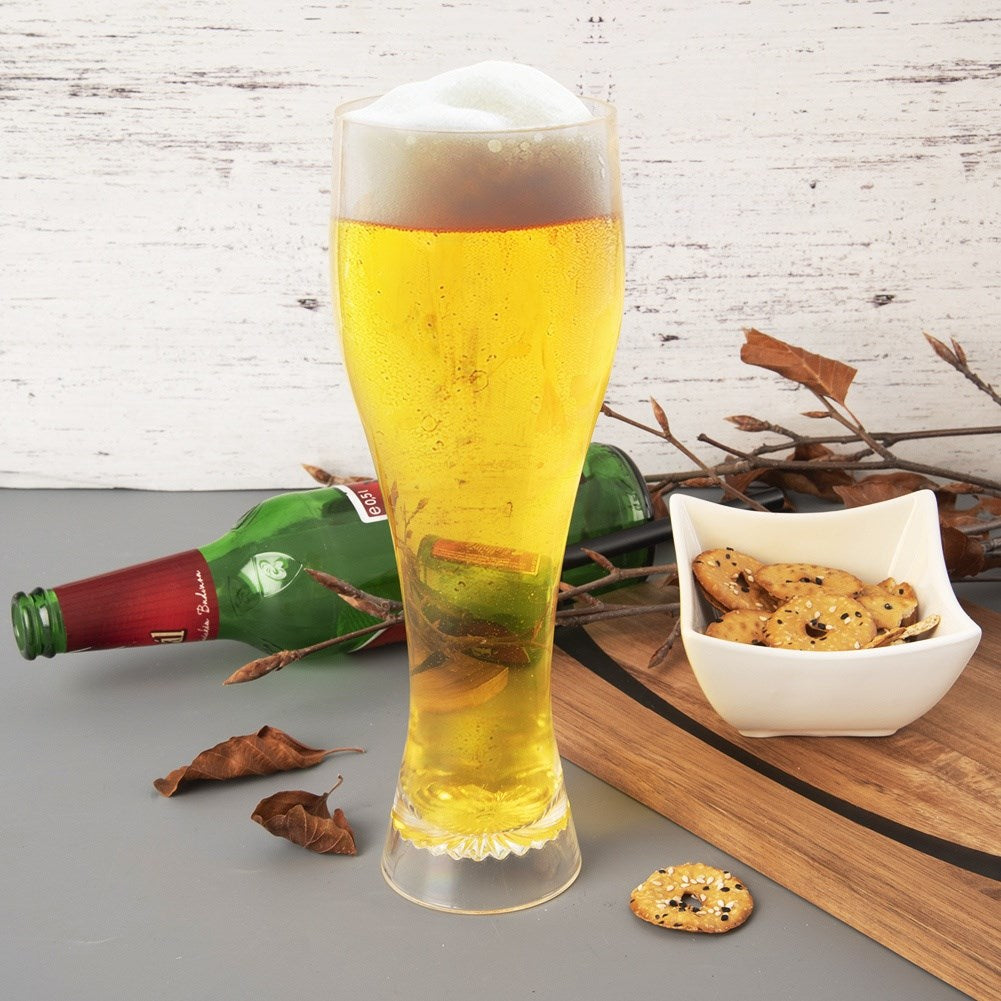 Un vaso de cerveza clara con espuma, al lado una botella verde y un cuenco con galletas.