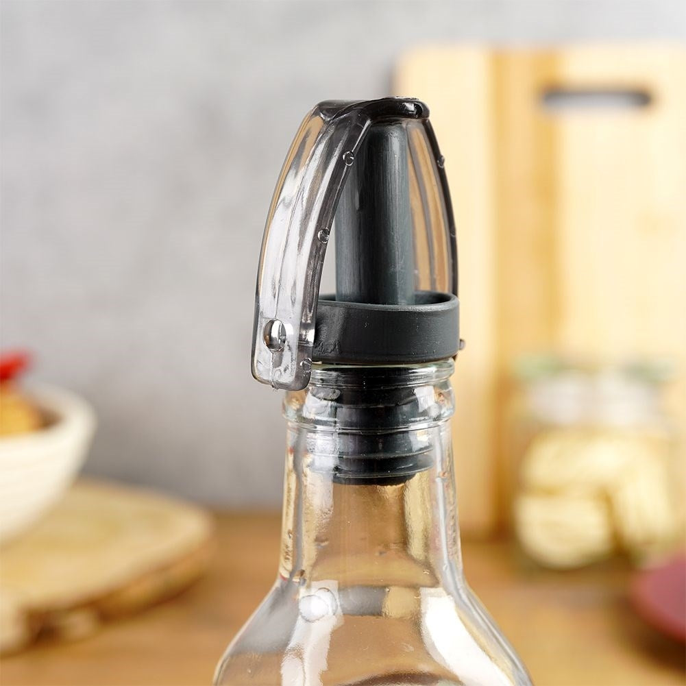 Un tapón de botella transparente con vertedor negro y tapa abatible.