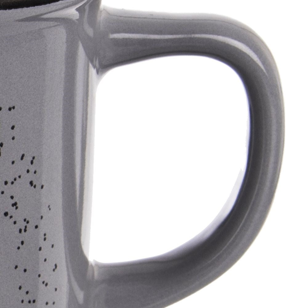 Taza gris con asa y puntos negros. Vista de cerca.