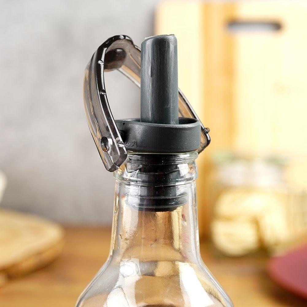 Primer plano de un tapón de botella de vidrio con asa transparente y pico vertedor gris.