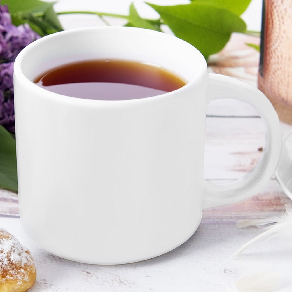 Una taza blanca de té con flores moradas y un pastel al lado.