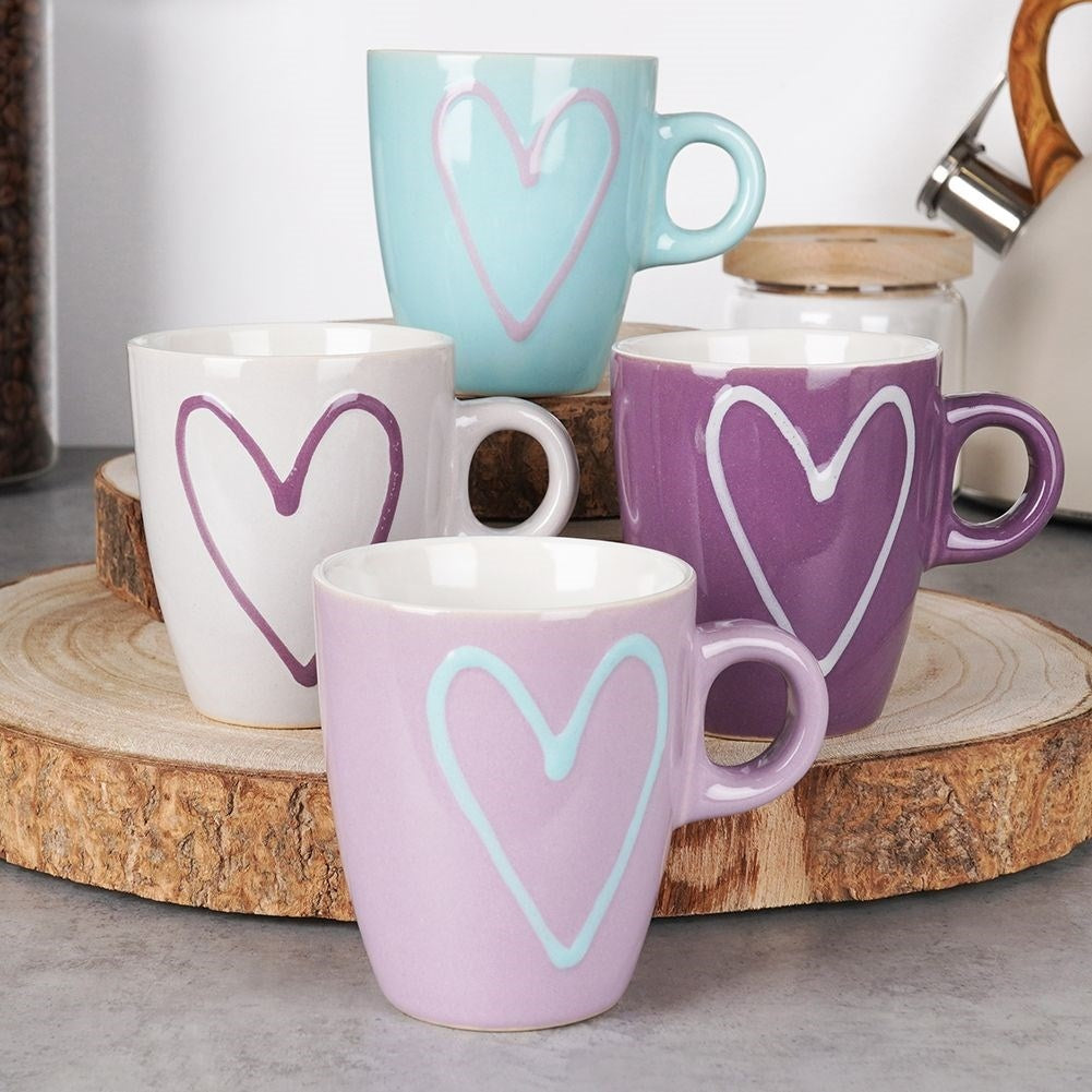 Cuatro tazas coloridas con diseños de corazón en un soporte de rodaja de madera.