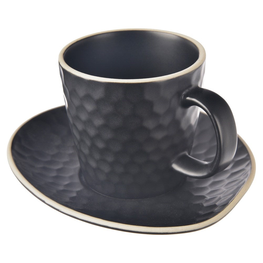 Una taza negra texturizada con patrón hexagonal sobre platillo a juego, aislada.
