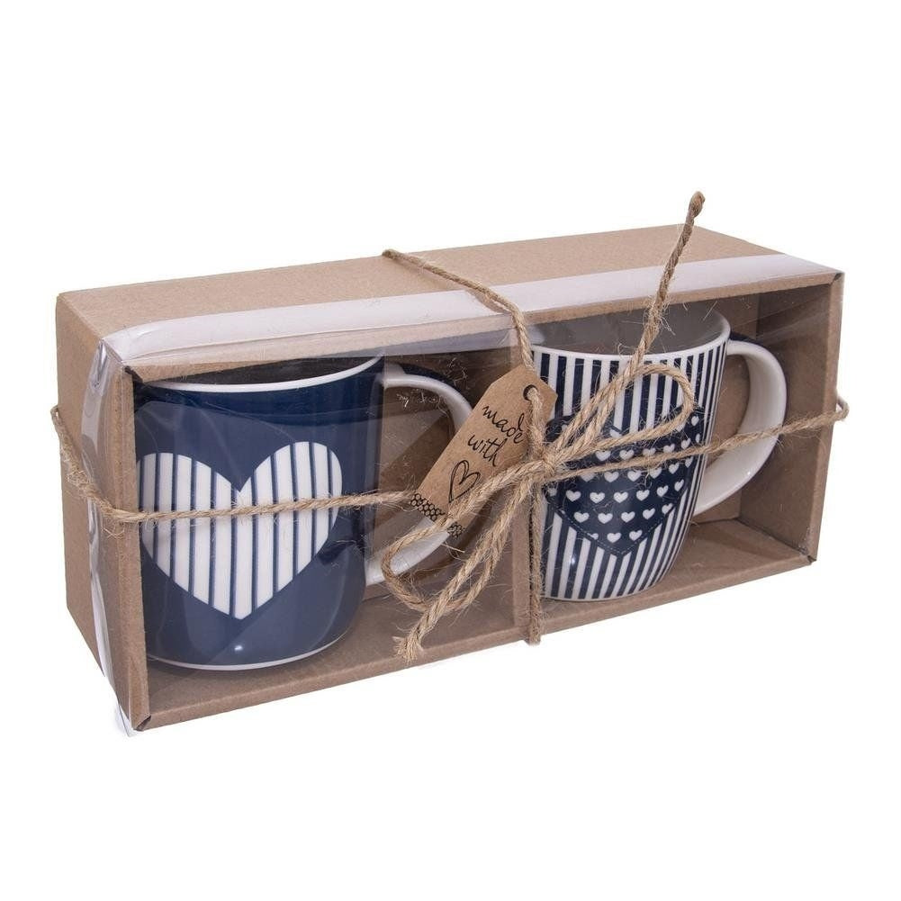Dos tazas azules con corazones blancos y rayas en una caja de regalo atada con cordel.