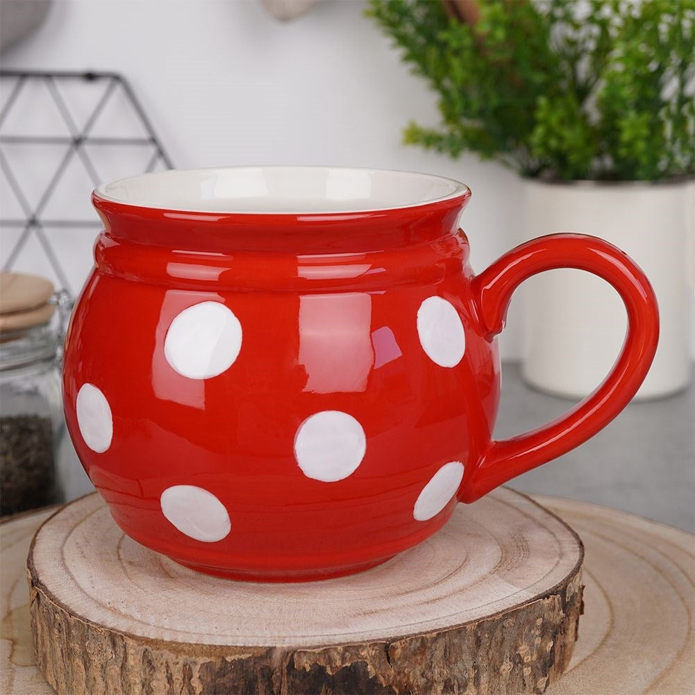 Una taza roja con lunares blancos está sobre un tronco de madera.