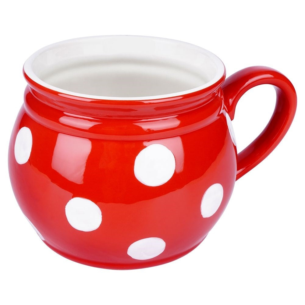 Una taza de cerámica roja con lunares blancos y un asa.