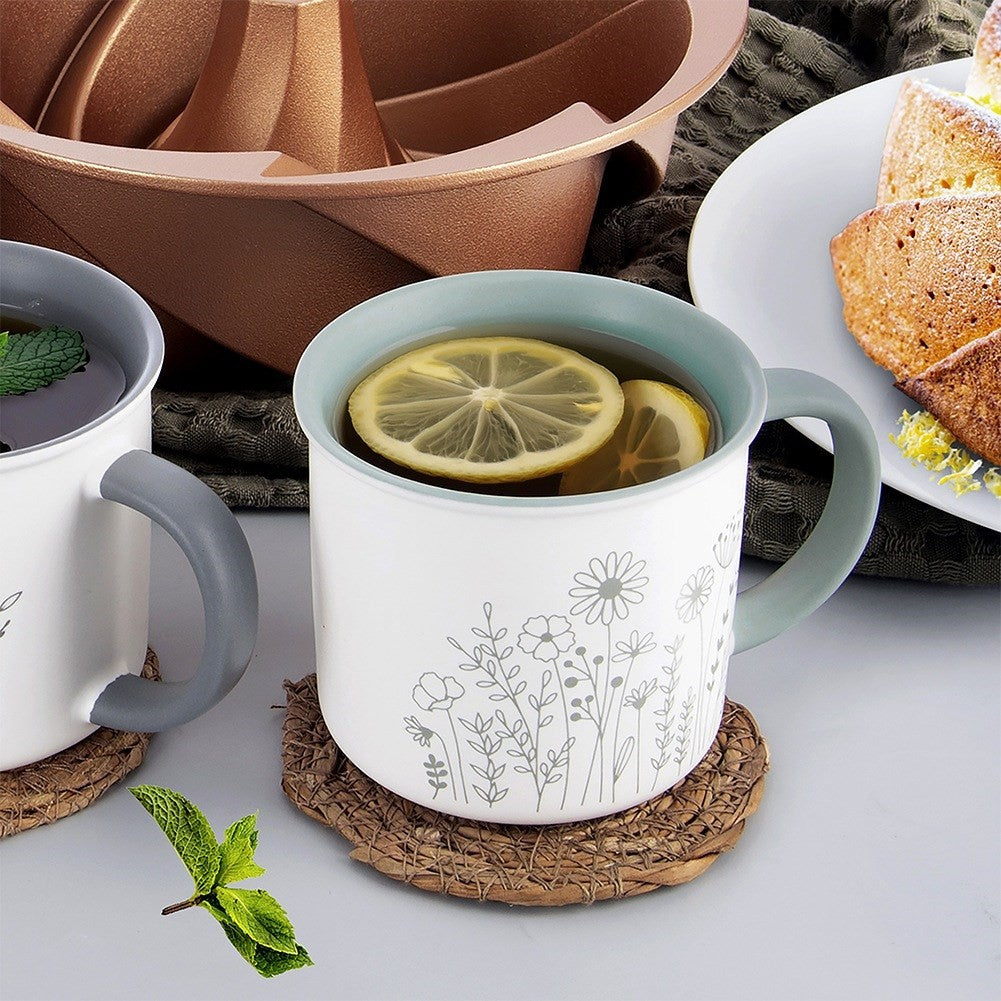 Dos tazas de té con limón y menta junto a una sartén de cobre y trozos de pastel.