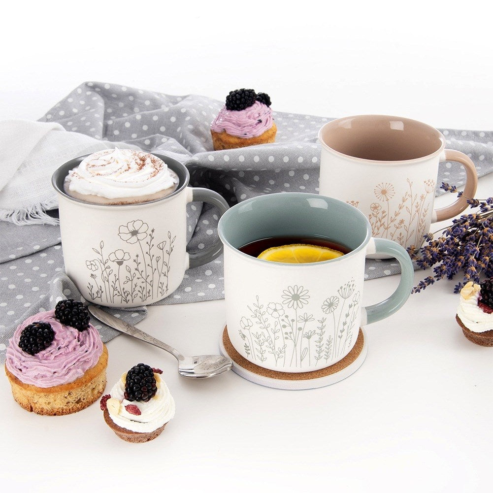 Tazas con diseños florales, cubiertas con cupcakes y bayas, dispuestas en una mesa.