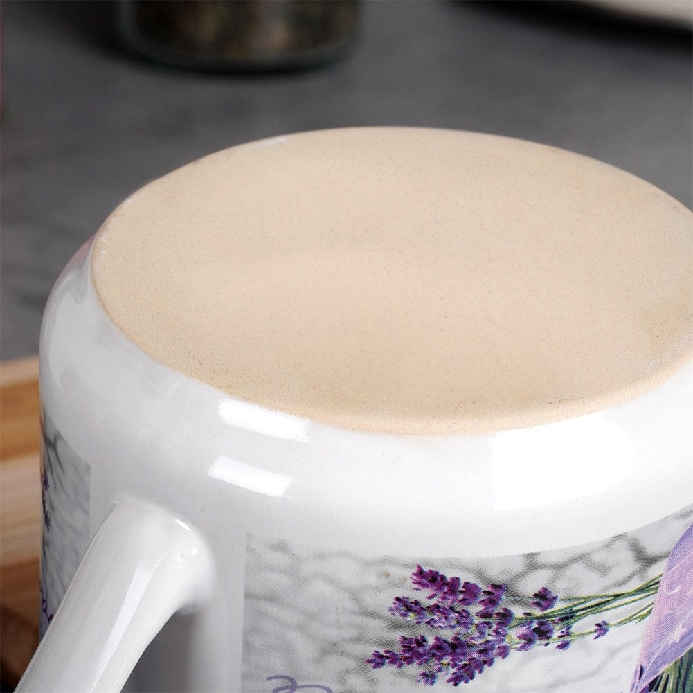 Primer plano de una taza blanca con diseño de lavanda y base sin esmaltar.