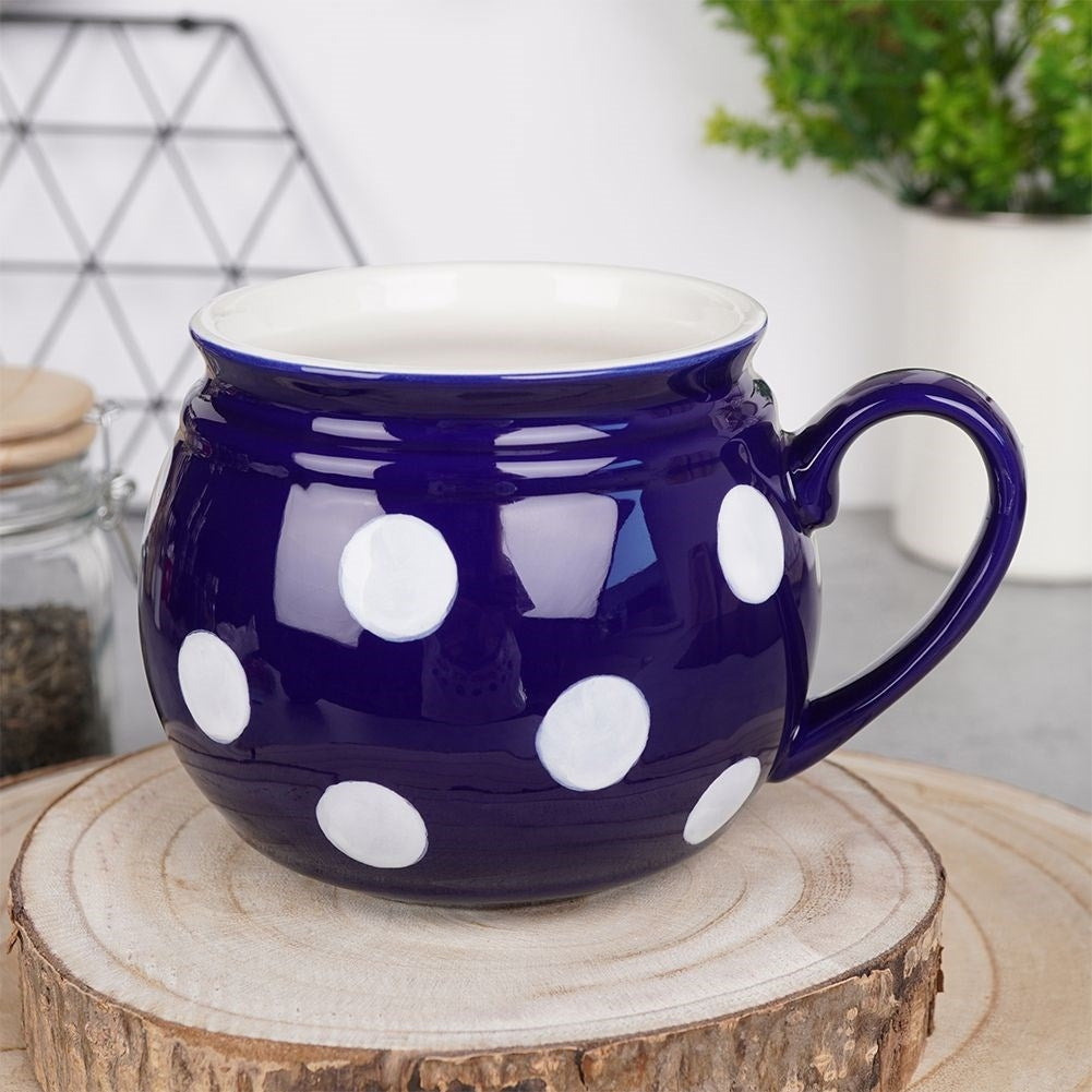Una taza azul oscuro con lunares blancos sobre un soporte de madera.