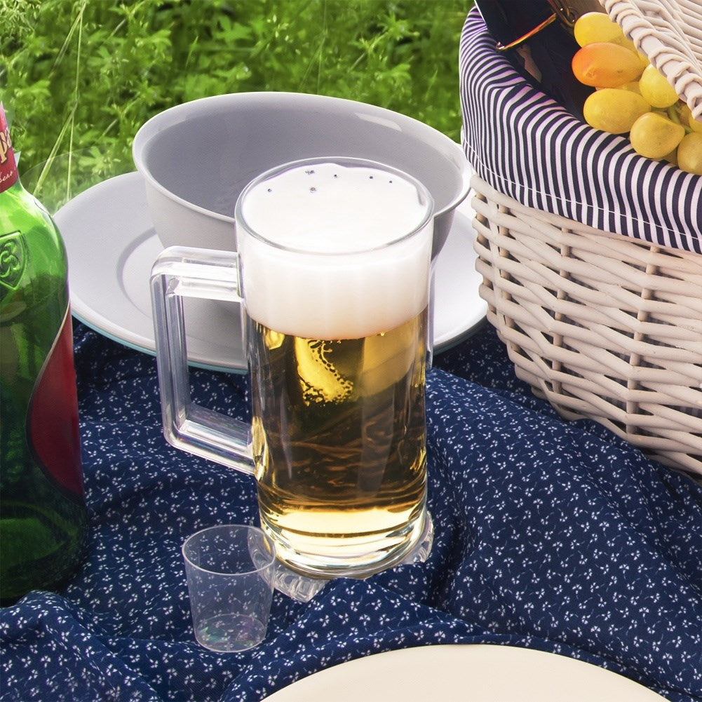 Una jarra de cerveza con espuma y una botella verde sobre una manta.