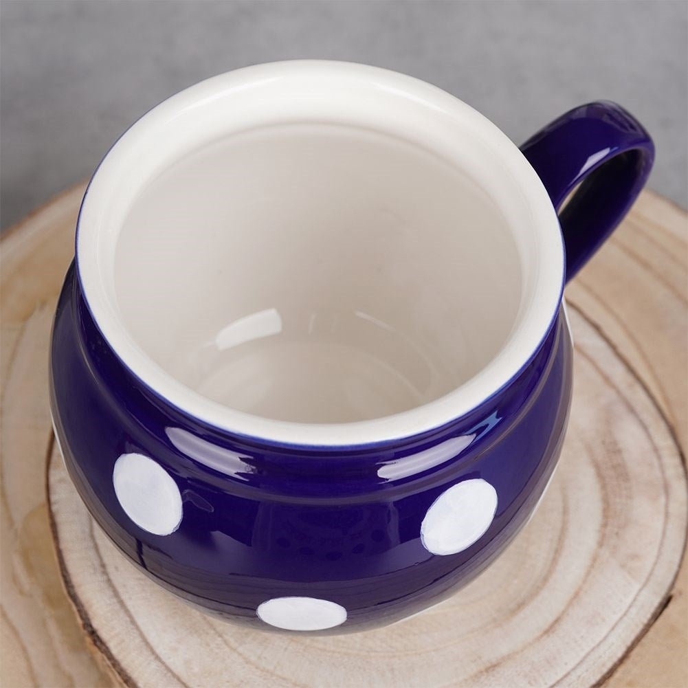 Una taza de cerámica azul con lunares blancos sobre una superficie de madera.