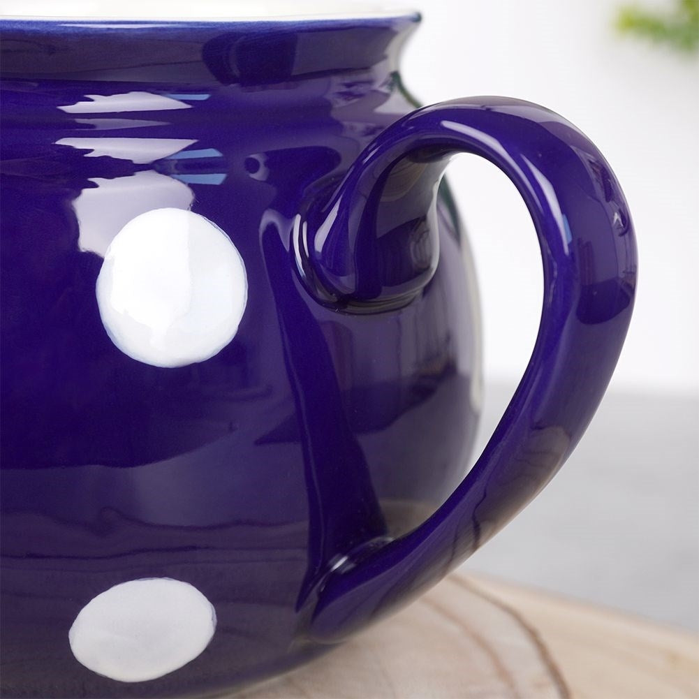 Taza de cerámica azul oscuro con lunares blancos y asa curva.