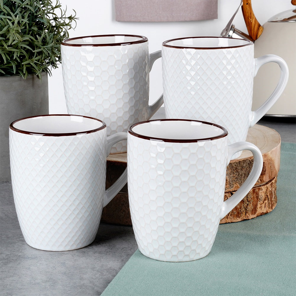 Cuatro tazas blancas texturizadas con bordes marrones están dispuestas sobre una mesa.