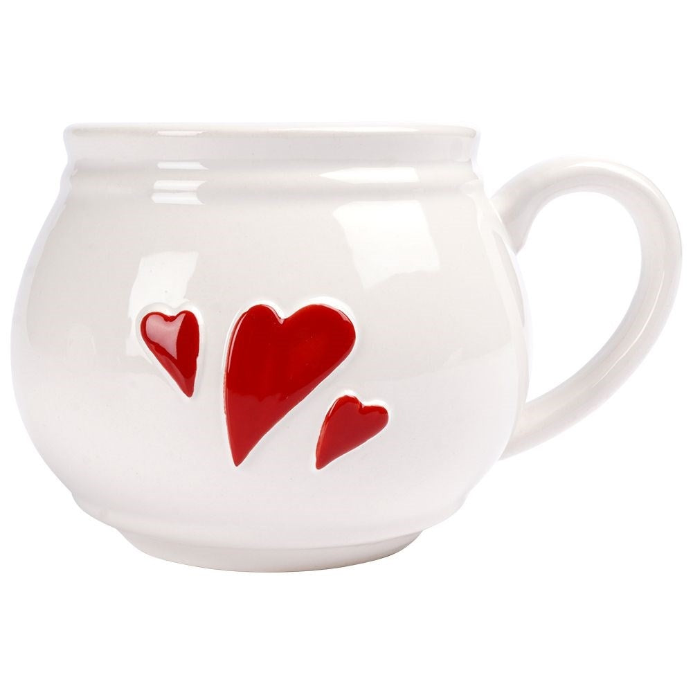 Una taza blanca con tres corazones rojos, dos grandes y uno pequeño.