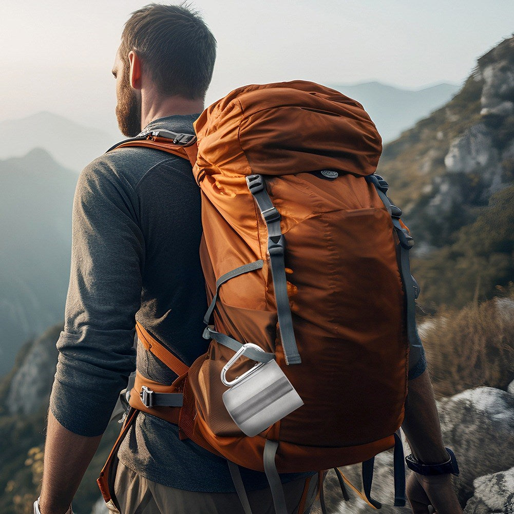 Hombre con mochila en montaña, taza colgada de la mochila.