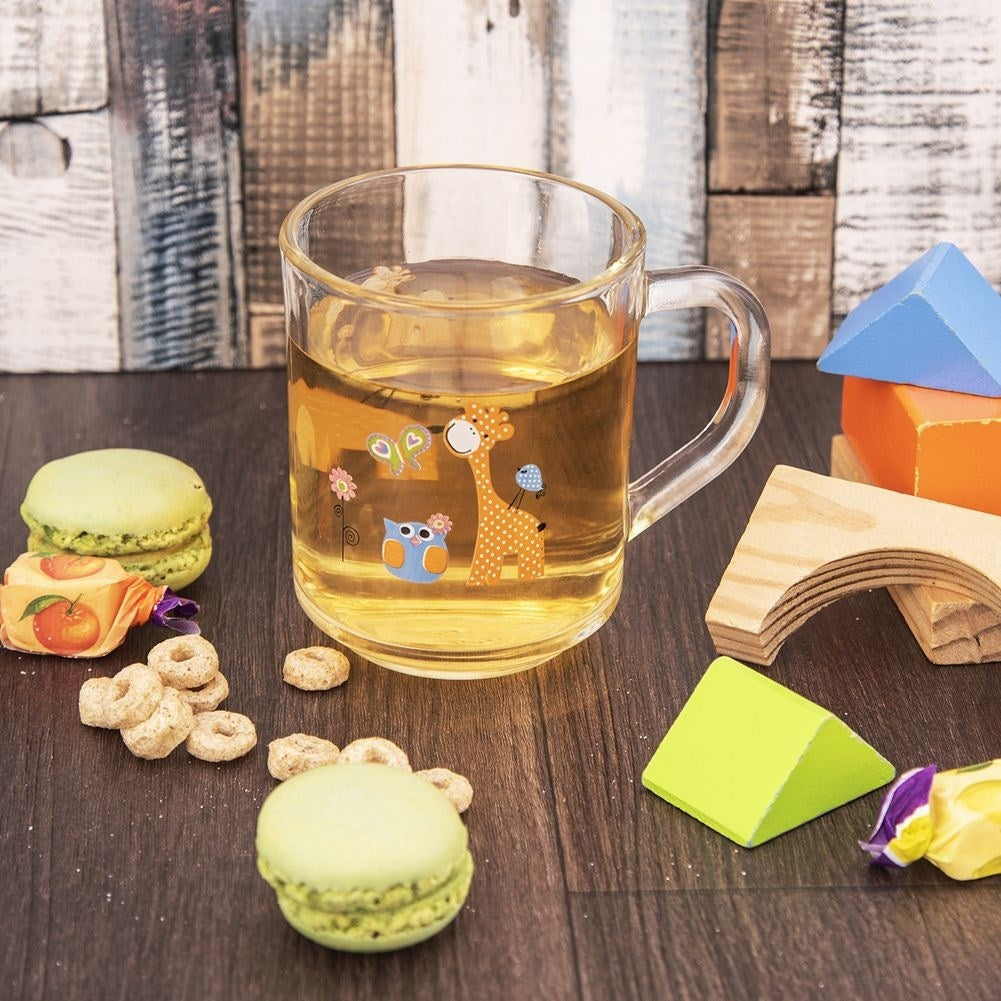 Taza de vidrio con té, macarons, cereales y juguetes de madera.