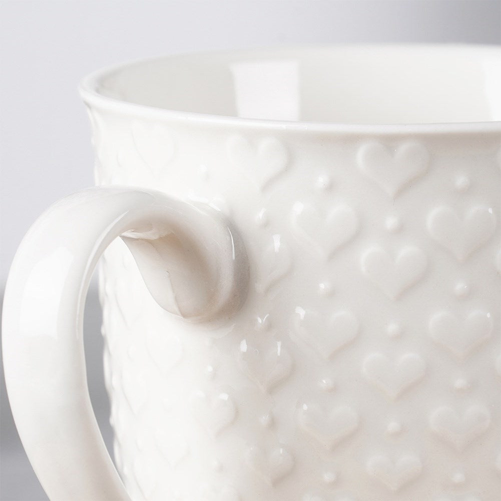 Taza blanca con estampado de corazón y asa, primer plano.
