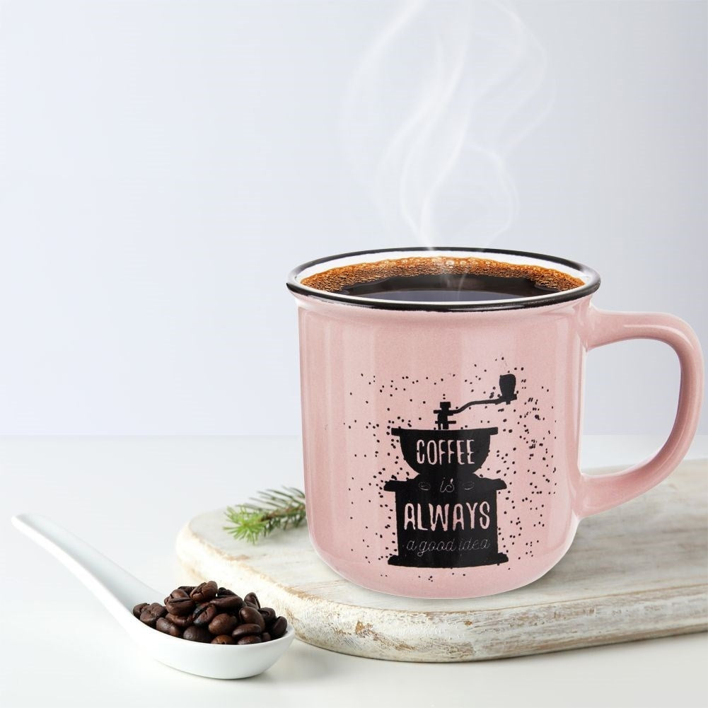 Una taza rosa de café humeante con granos y una ramita de pino.