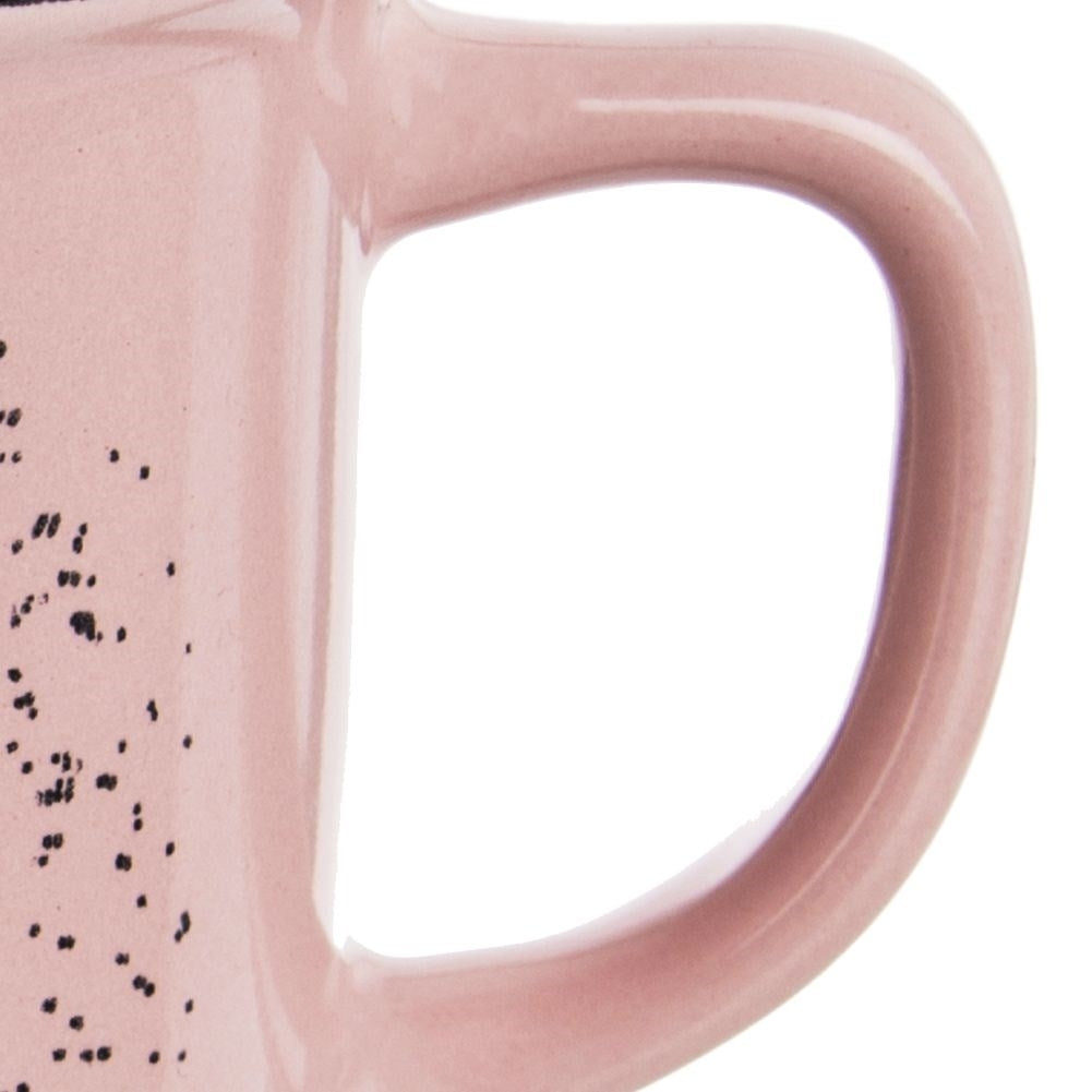 Primer plano de una taza rosa con motas negras y un asa.