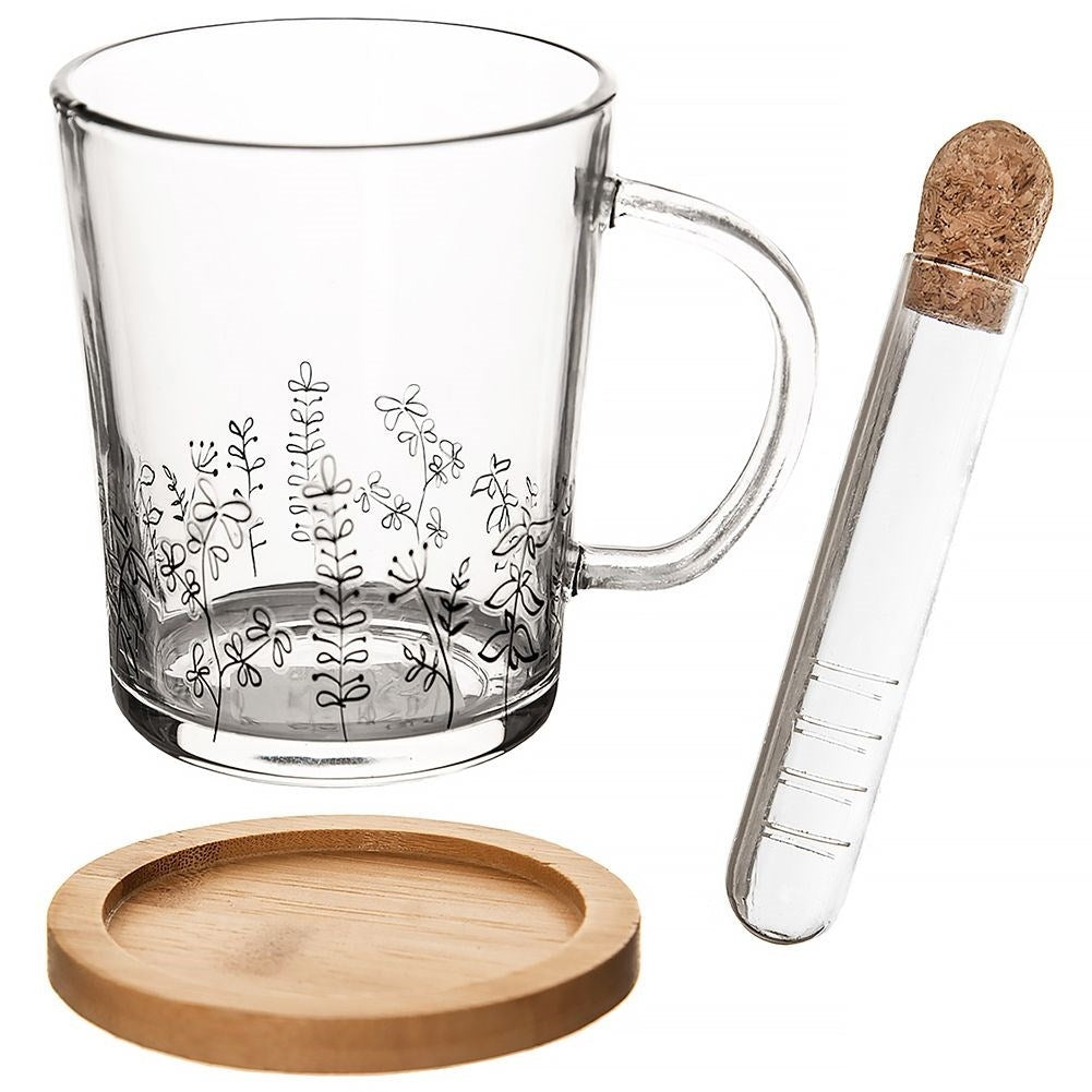 Taza de cristal con estampado floral, posavasos de madera y tubo con tapón de corcho.