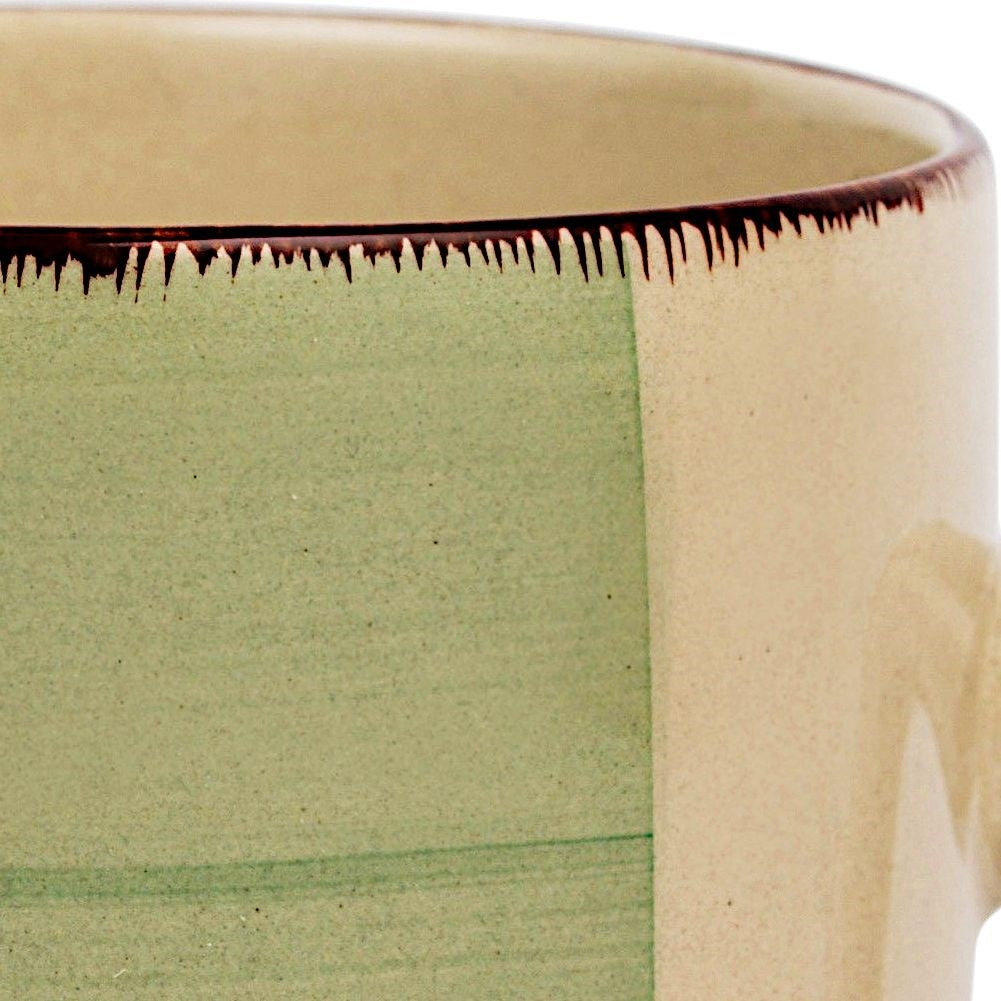 Primer plano de una taza con secciones verdes y crema y borde marrón.