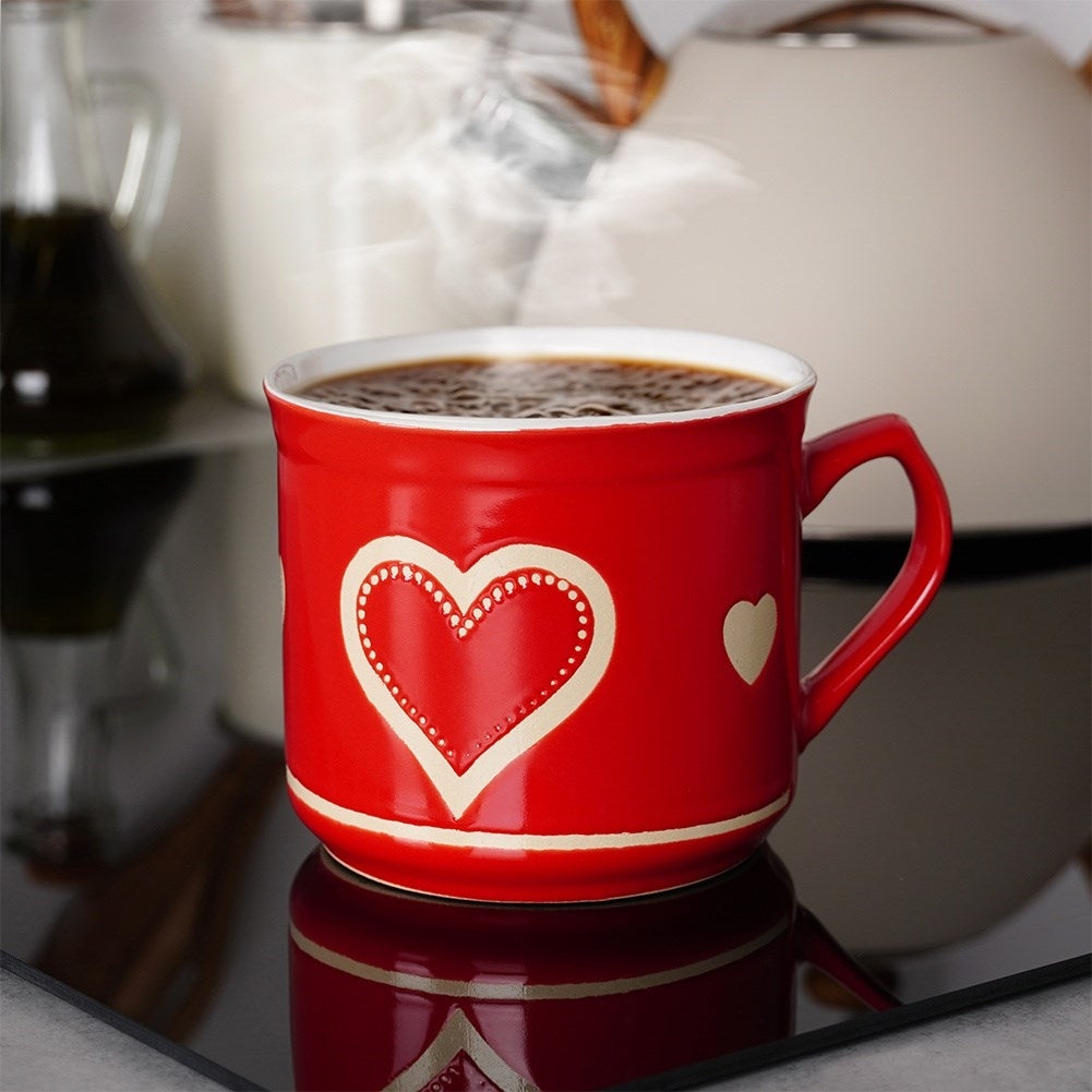 Una taza roja con diseños de corazón, llena de café caliente, humea.