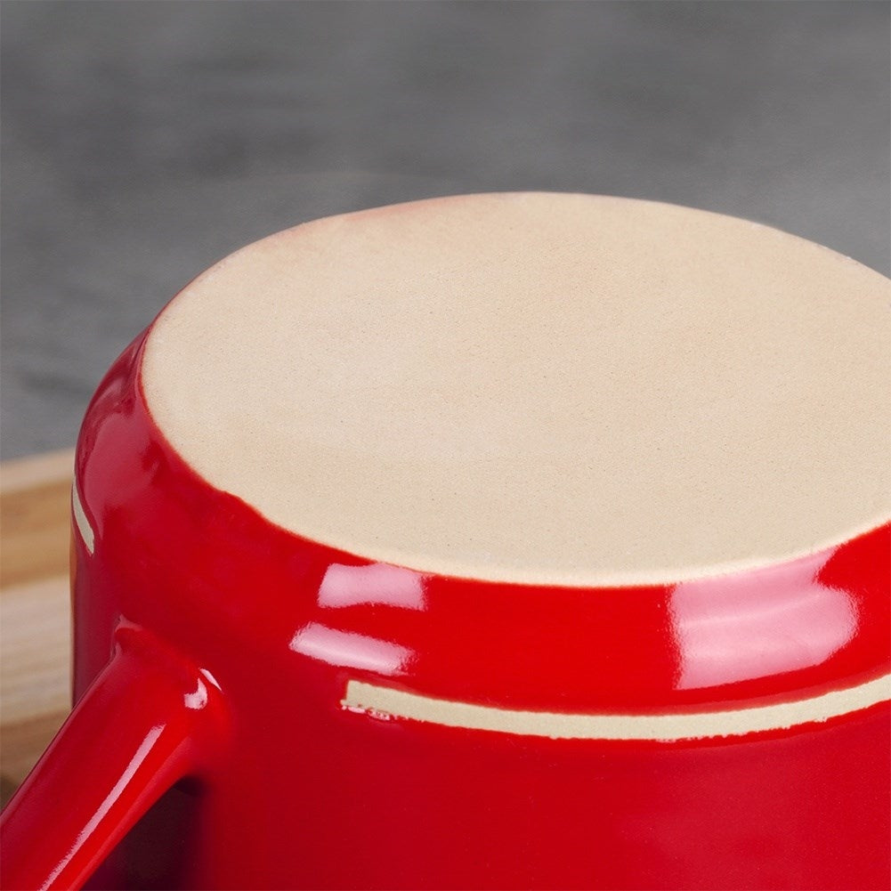 Taza de cerámica roja con borde claro, vista de cerca.