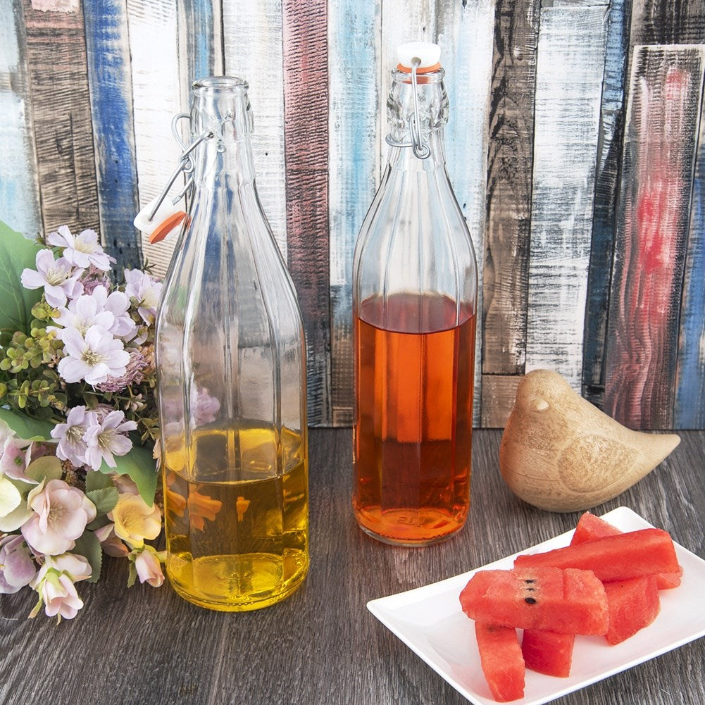 Dos botellas con líquido, sandía y flores sobre una mesa de madera.