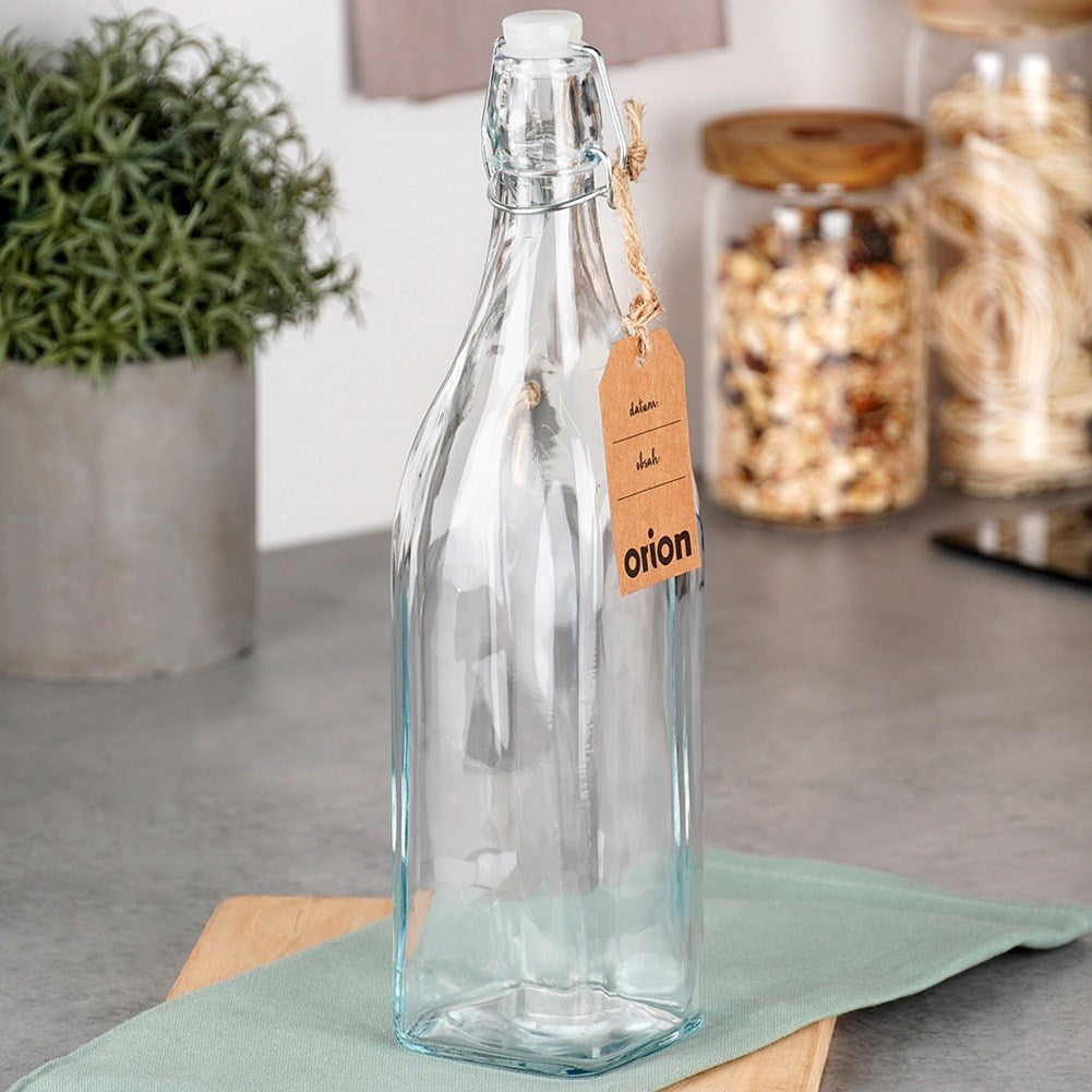 Una botella de vidrio vacía con tapón de palanca y etiqueta marrón.