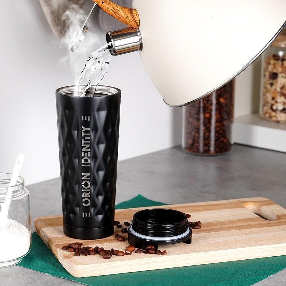 Se vierte agua caliente en un vaso negro. Hay granos de café y azúcar cerca.