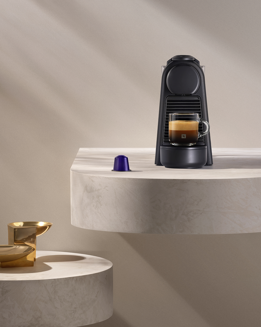 Una macchina Nespresso nera con una tazza di espresso e una capsula.