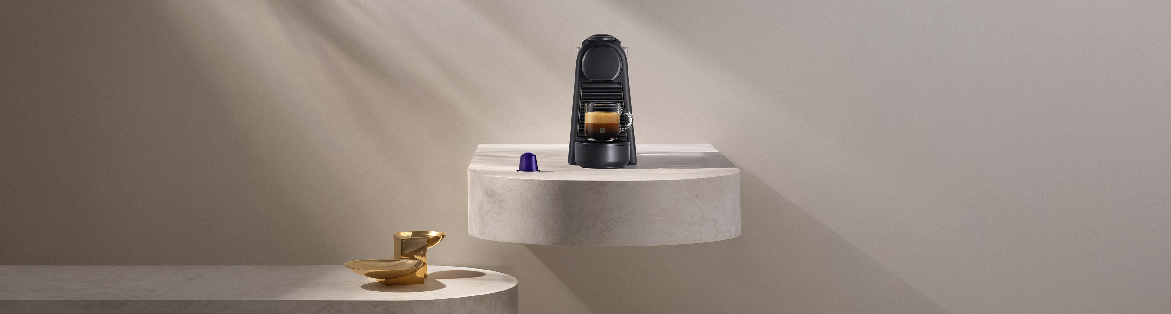 Macchina da caffè nera con caffè in tazza e capsula accanto.