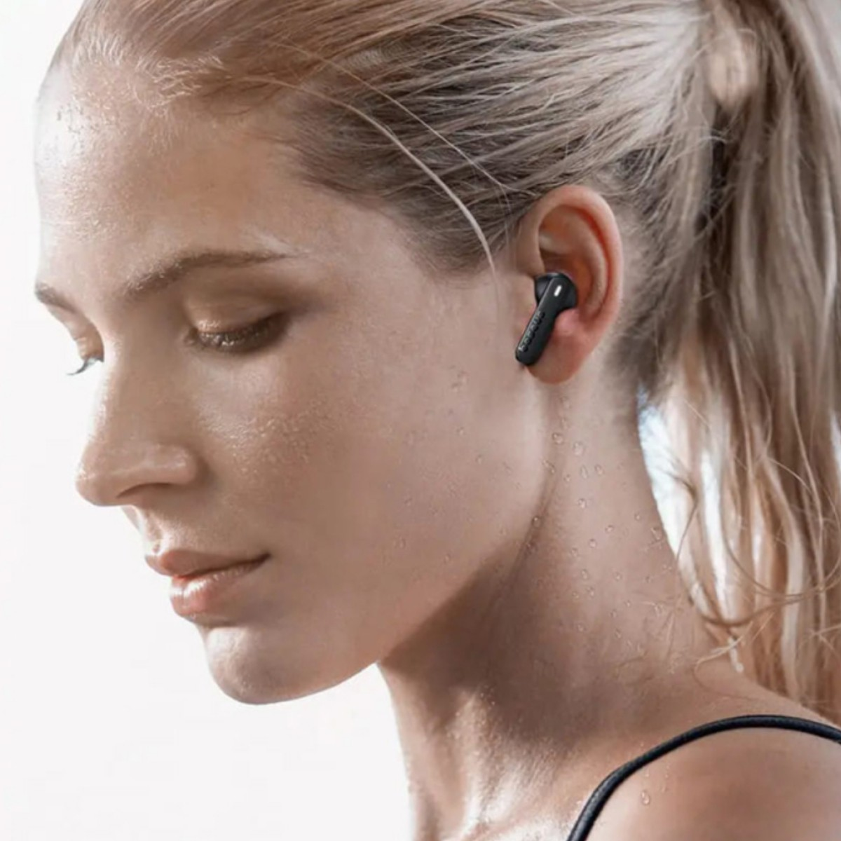 Una donna con un auricolare nero nell'orecchio, il viso è sudato.