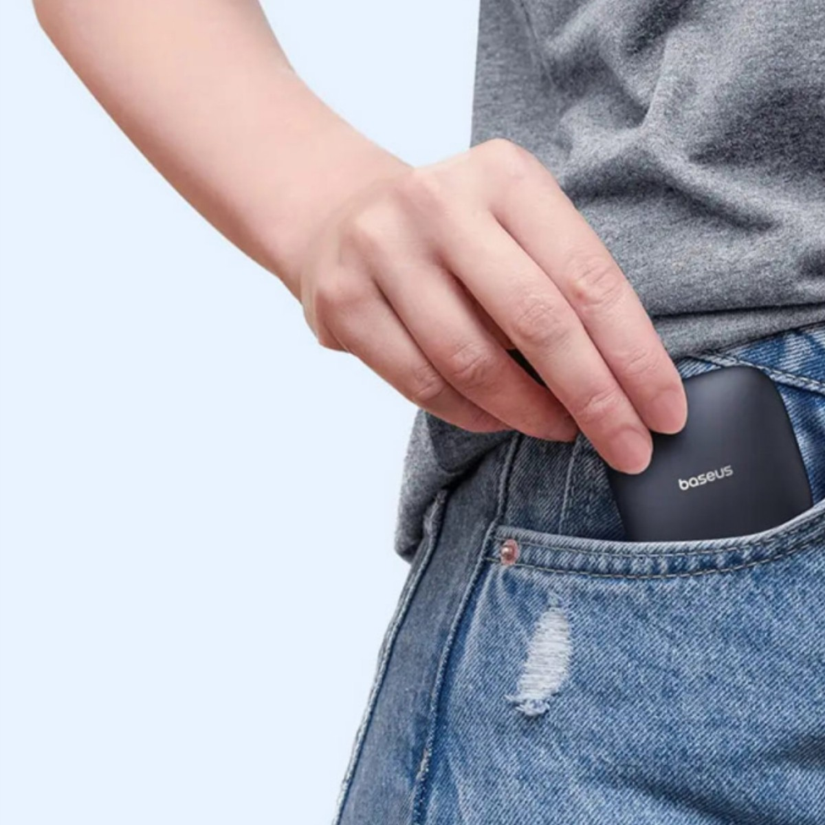 Una mano infila un dispositivo nero Baseus in una tasca di jeans.