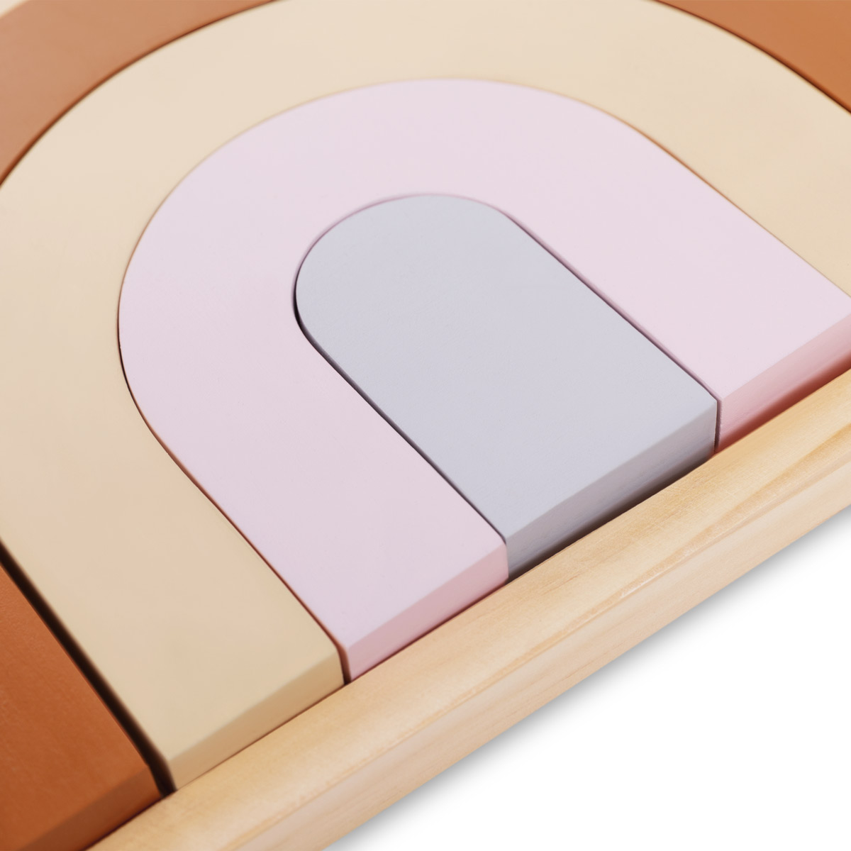 Rompecabezas de arcoíris de madera en tonos marrones, beige, rosa y gris.
