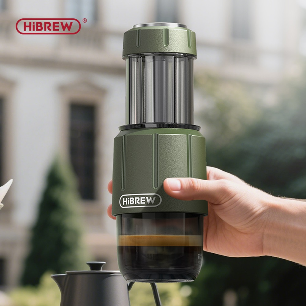 Cafetera verde sostenida en la mano, con café en el recipiente de vidrio.
