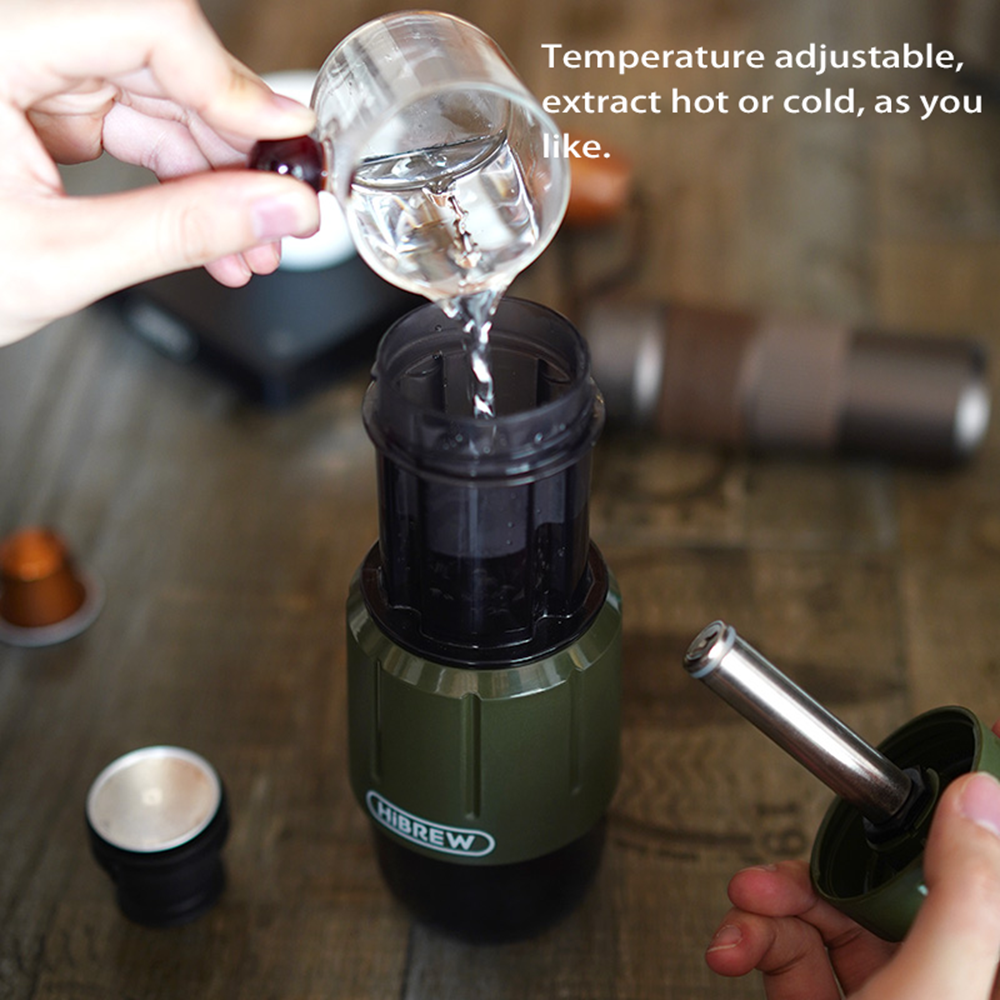 Se vierte agua de un vaso a una cafetera verde.
