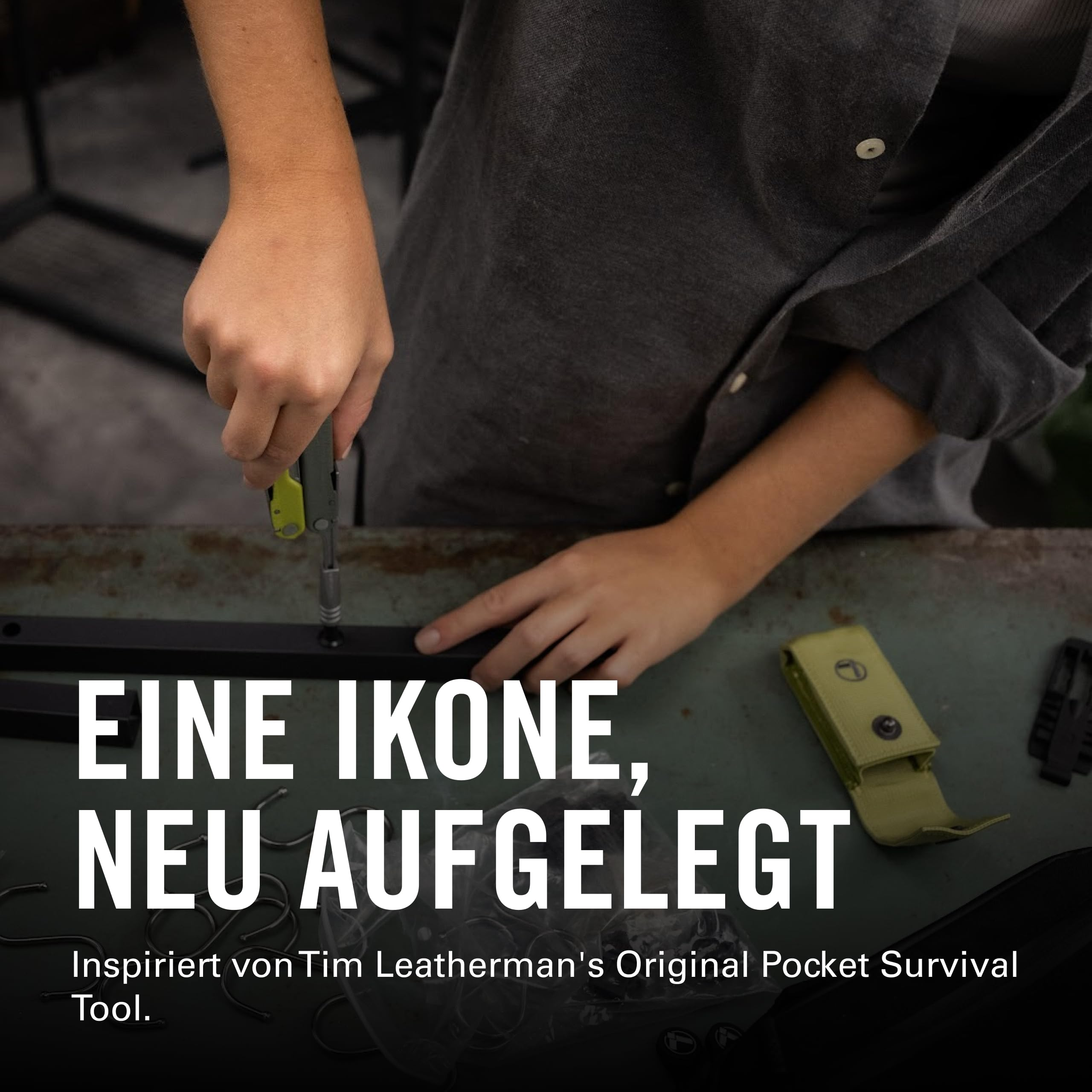 Person schraubt an einem schwarzen Metallrahmen. Grüne Werkzeugtasche daneben.