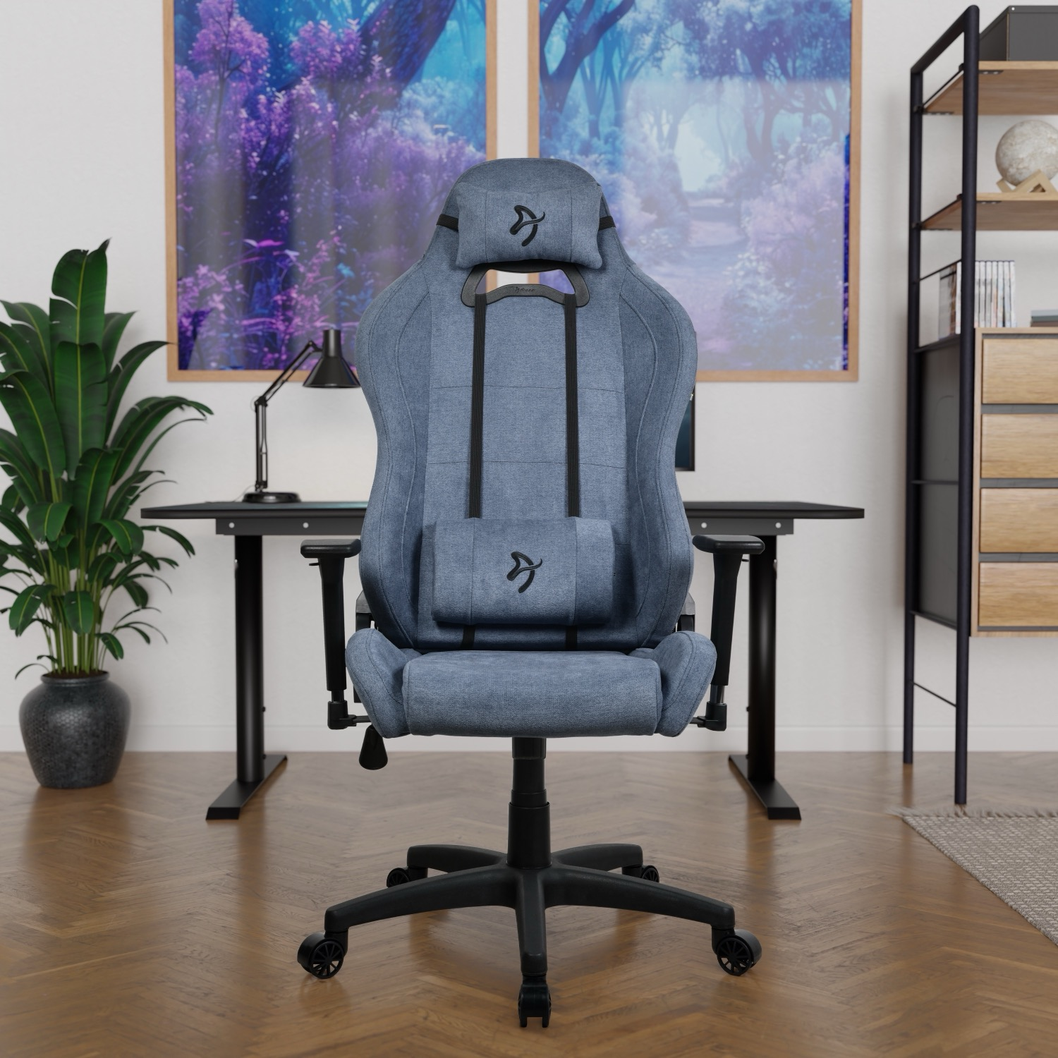 Een blauwe gamestoel staat voor een bureau met twee kunstwerken op de achtergrond.