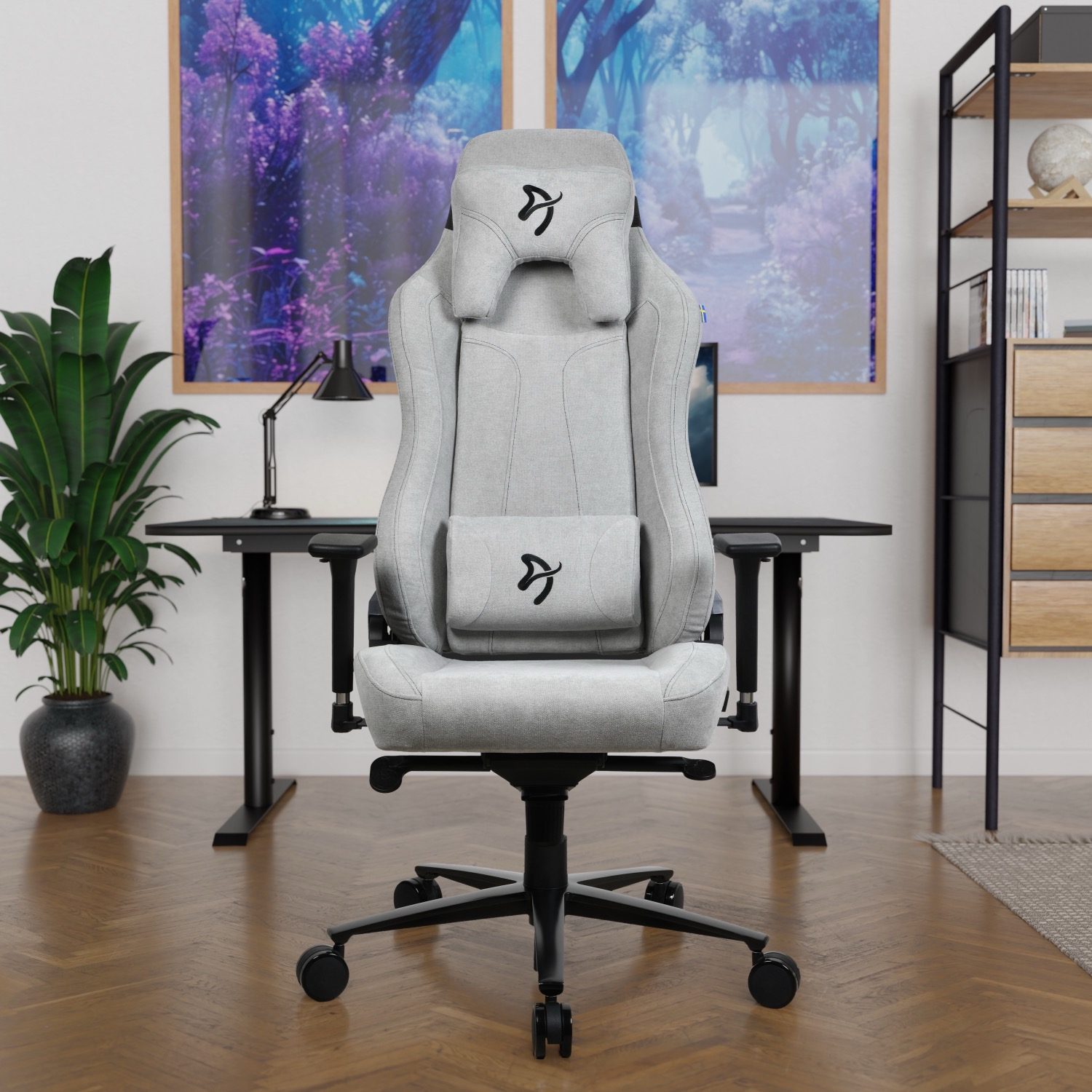 Een grijze gamestoel staat voor een bureau met twee schilderijen op de achtergrond.