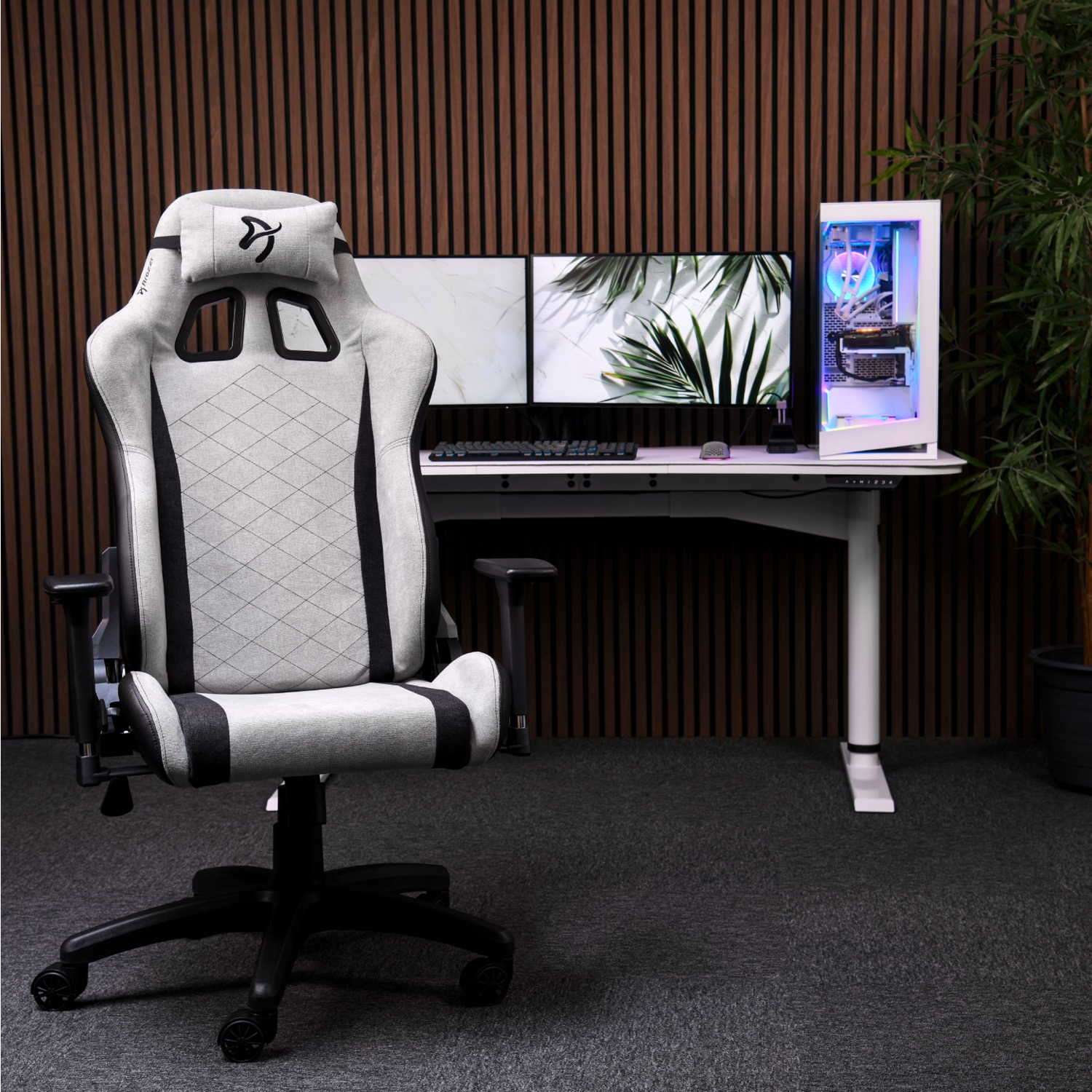 Een lichtgekleurde gamestoel staat voor een bureau met twee monitoren en een pc.