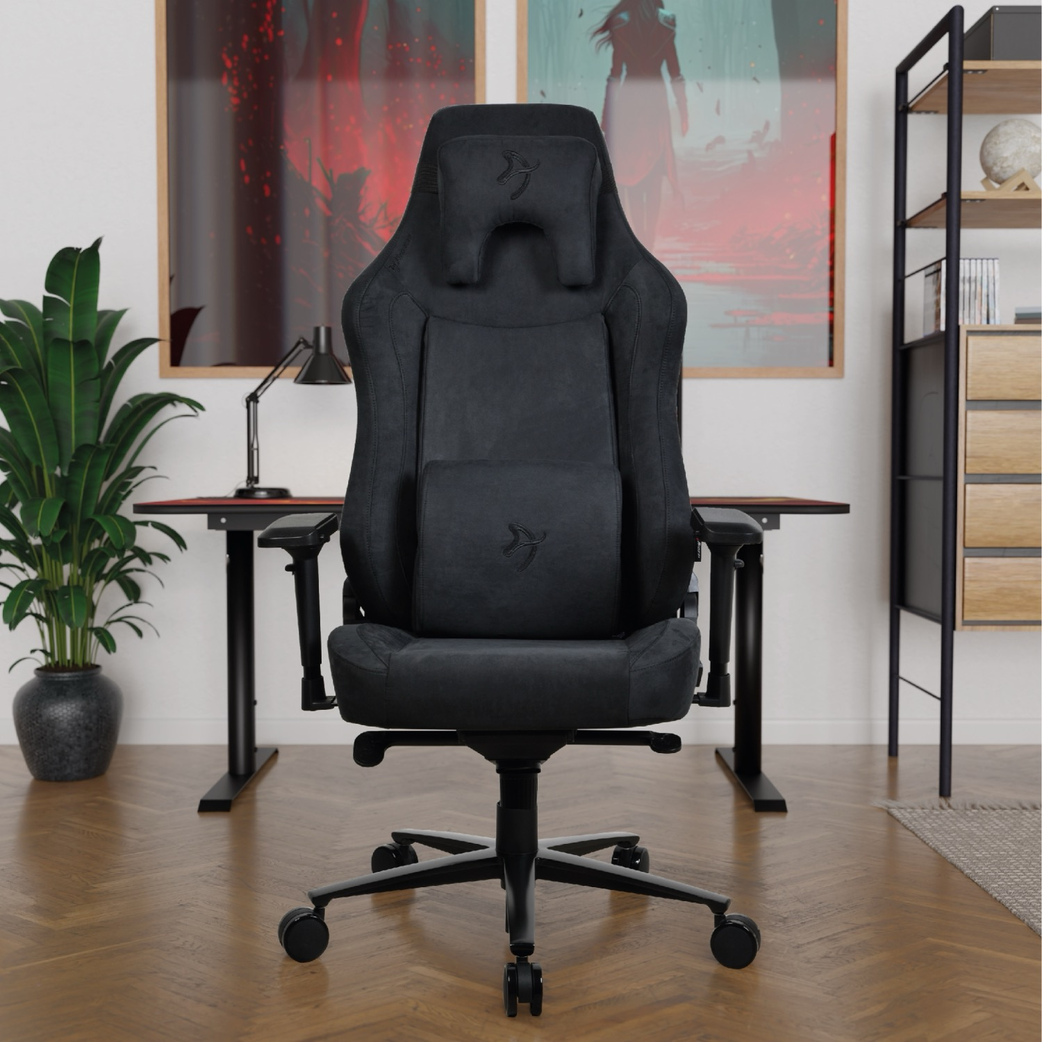 Een zwarte gamestoel staat voor een bureau met kunst aan de muur.