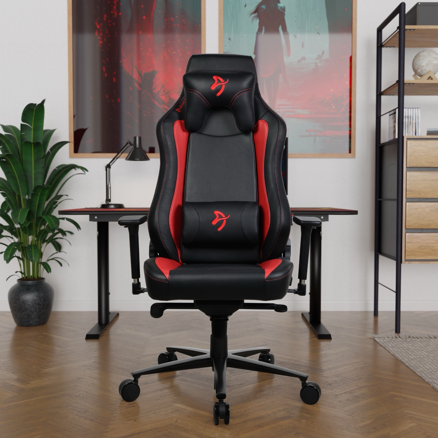 Zwarte gamestoel met rode accenten, voor een bureau en schilderijen.