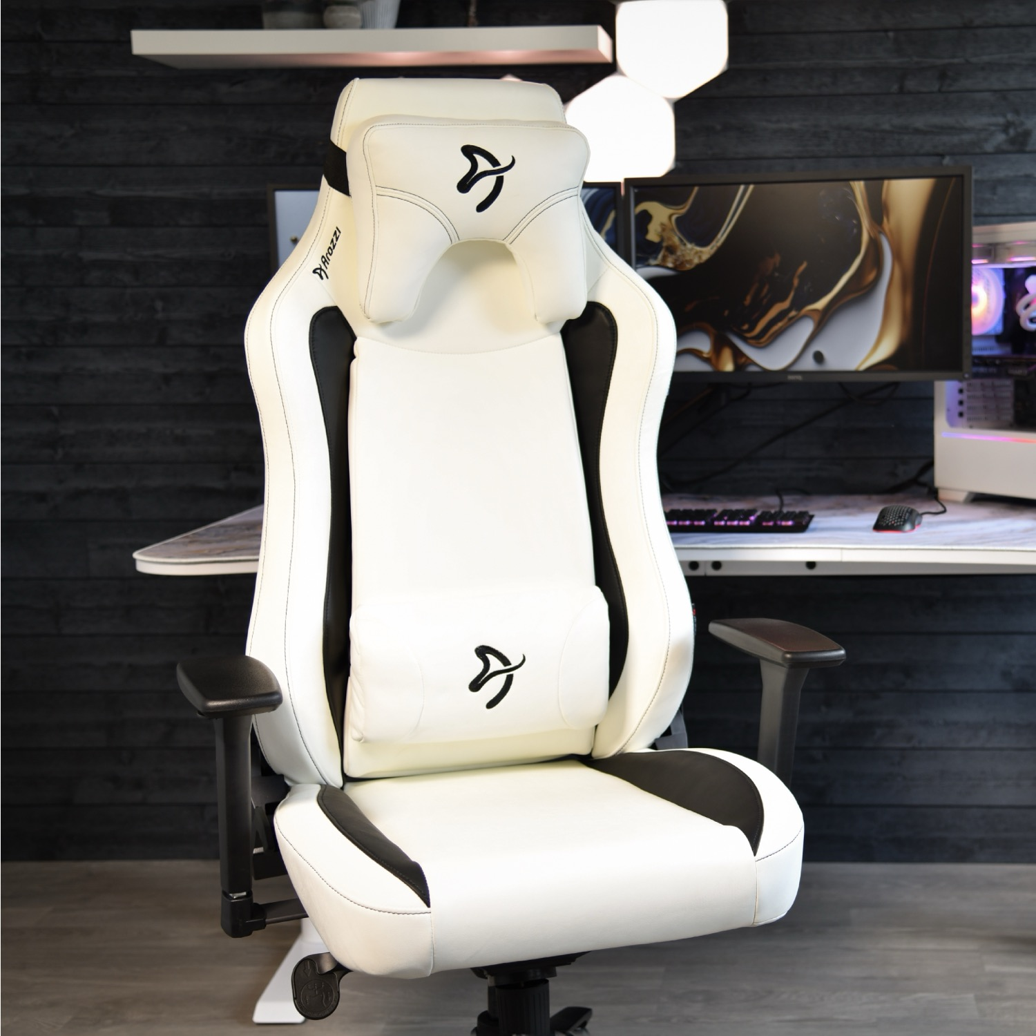 Een witte gamestoel met zwarte accenten staat voor een bureau met computerapparatuur.